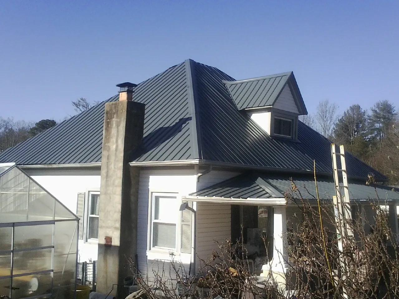 Dark blue standing seam metal roof on a white farmhouse with dormer — Slate & Tile Roof Repair by Roofing Brothers in Arcadia