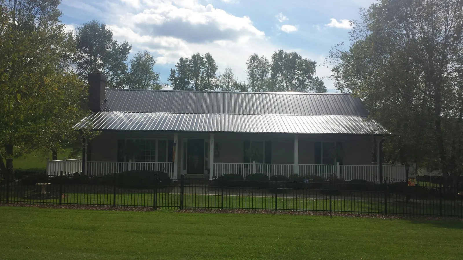 Gray metal roof on a brick ranch with a full width front porch — Gutter Guard Installation work by our crew in Arcadia