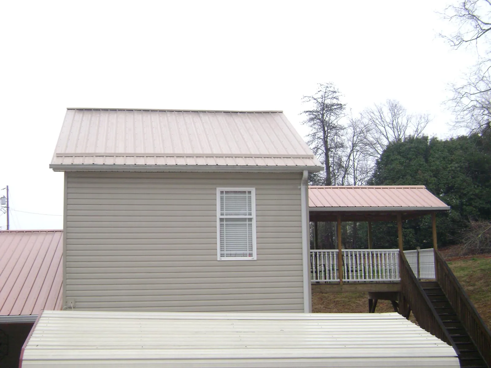 Tan metal roofs on a two story addition and attached porch, from a Roof Replacement job in Arcadia